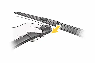 Hand pressing the release tab to detach a windshield wiper blade from the wiper arm.
