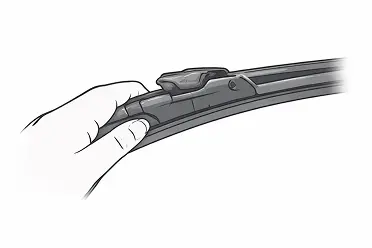 Close-up of a hand snapping a windshield wiper blade into place on a car.